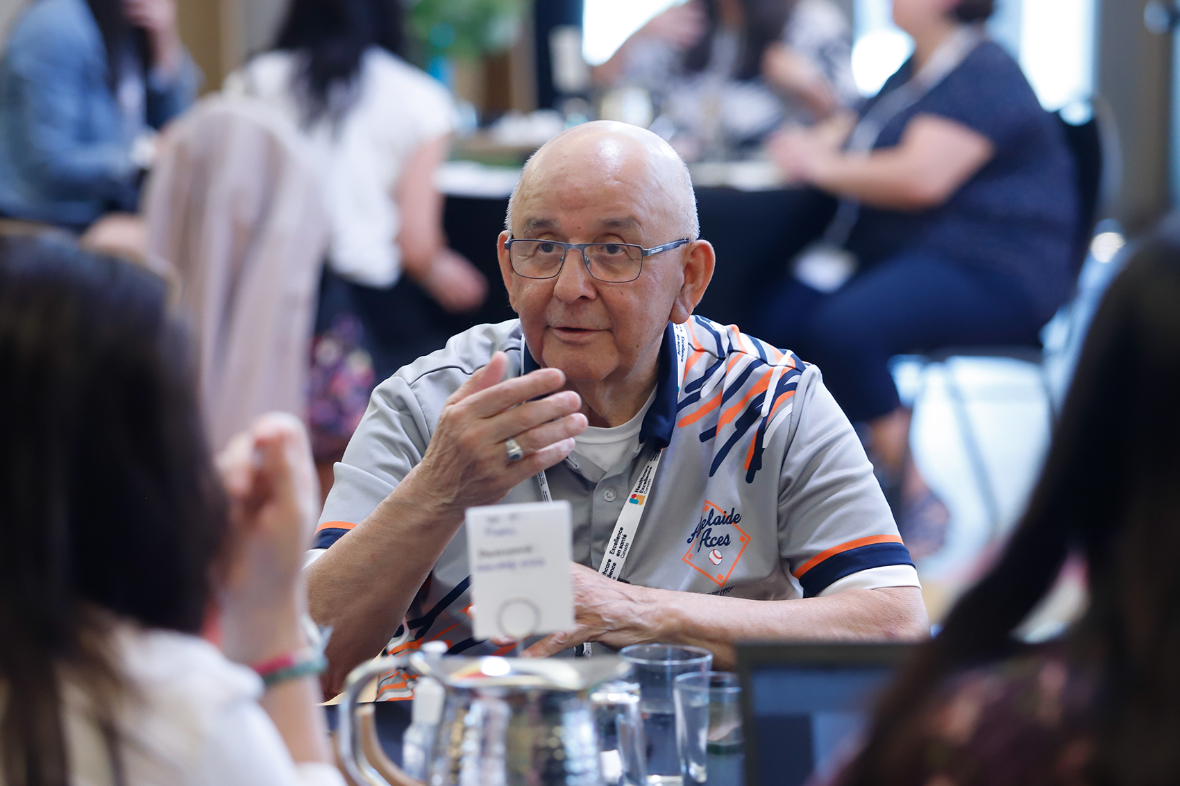 Image of Elder Wally Sinclair engaging in discussion with participants seated around a table at the Cultural Safety Design Collaborative event held in Ottawa, ON, in June 2023.